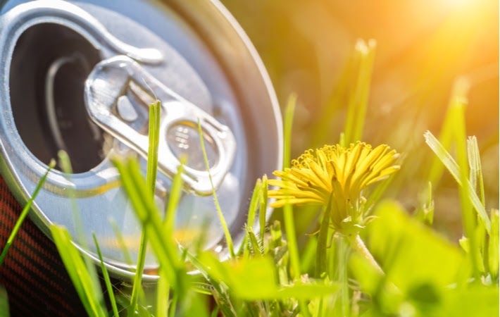 An aluminum can laying on green grass showing the positive influence metal recycling has on the environment