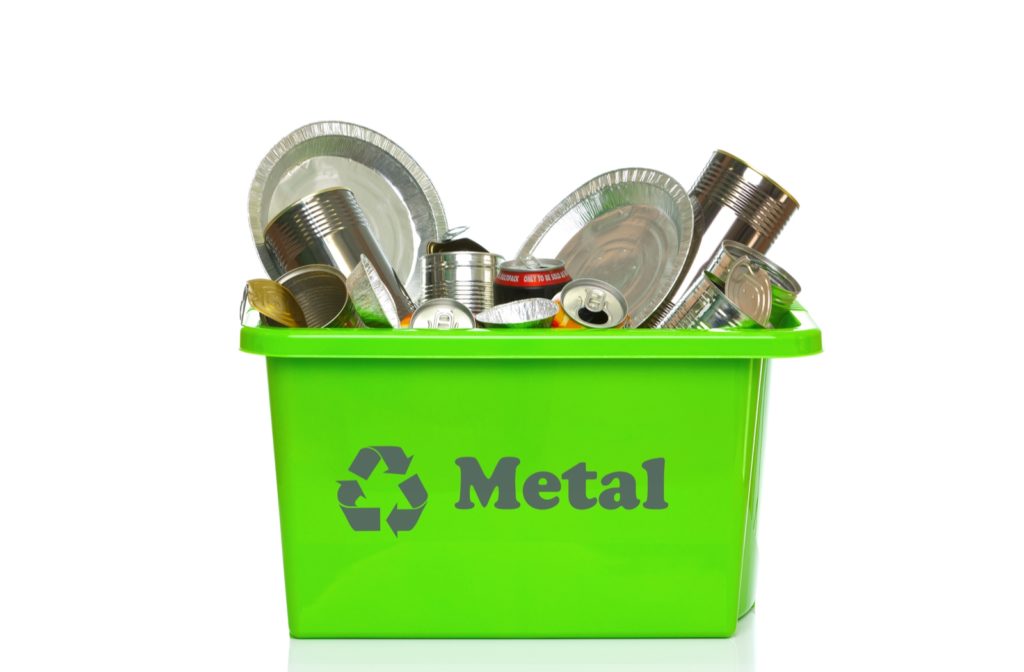A green bin with a recycling icon and the word metal on the front, filled with metal ready to be recycled