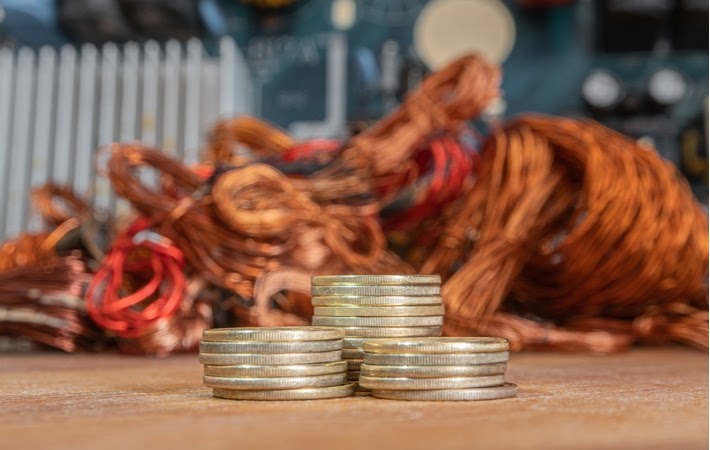 Stack of coins in front of copper showing the incentive to scrap copper