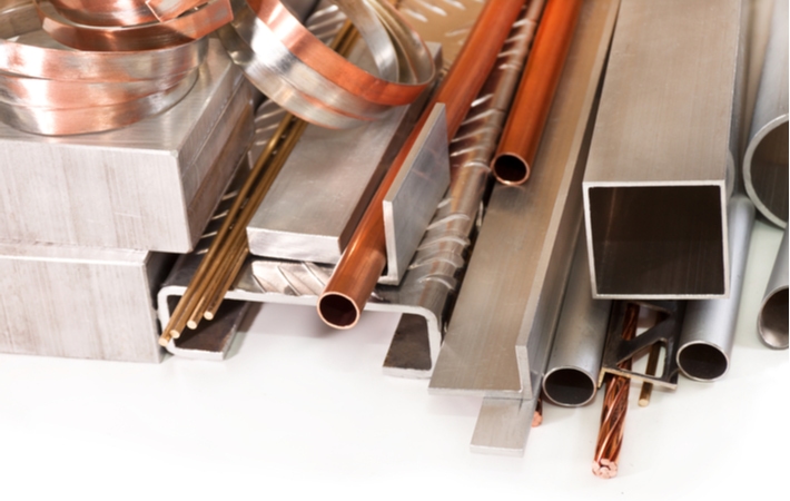 A collection of assorted scrap metal including copper and steel laying on a white surface