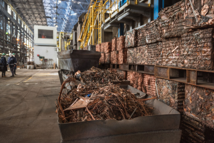 Inside of a metal recycling facility with bins and crushed cubes of copper ready to be recycled